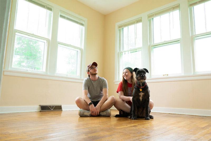 新房主夫妇和他们的狗在空荡荡的客厅里